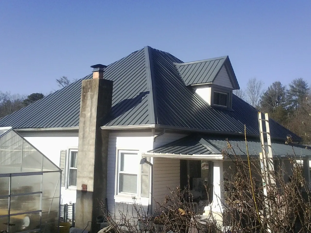Dark blue standing seam metal roof on a white farmhouse with dormer — Slate & Tile Roof Repair by Roofing Brothers in Holmdel