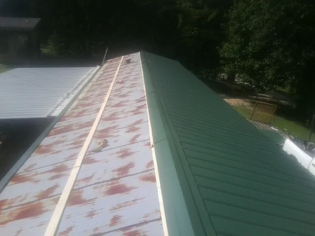 Old rusted panels beside newly installed green metal roofing — Wind Damage Roof Repair by Roofing Brothers in Holmdel