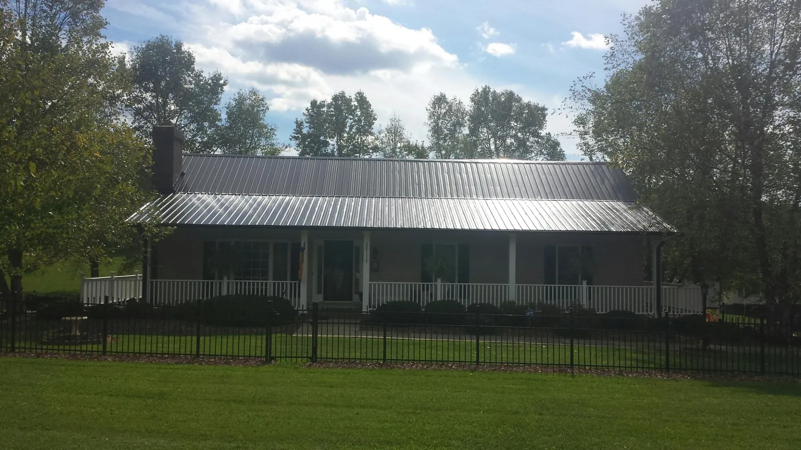 Gray metal roof on a brick ranch with a full width front porch — Gutter Guard Installation work by our crew in Holmdel