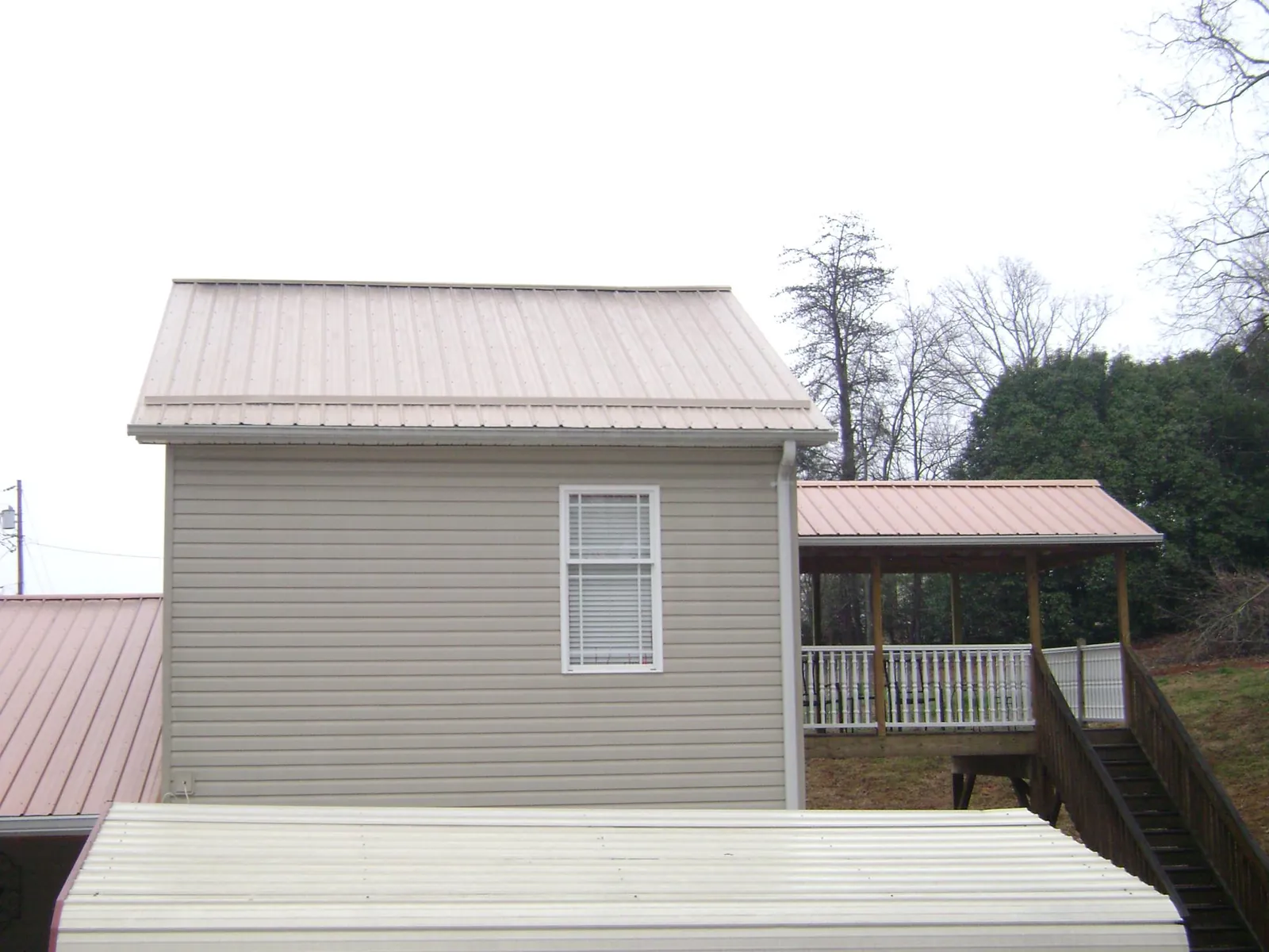 Tan metal roofs on a two story addition and attached porch, from a Roof Replacement job in Holmdel