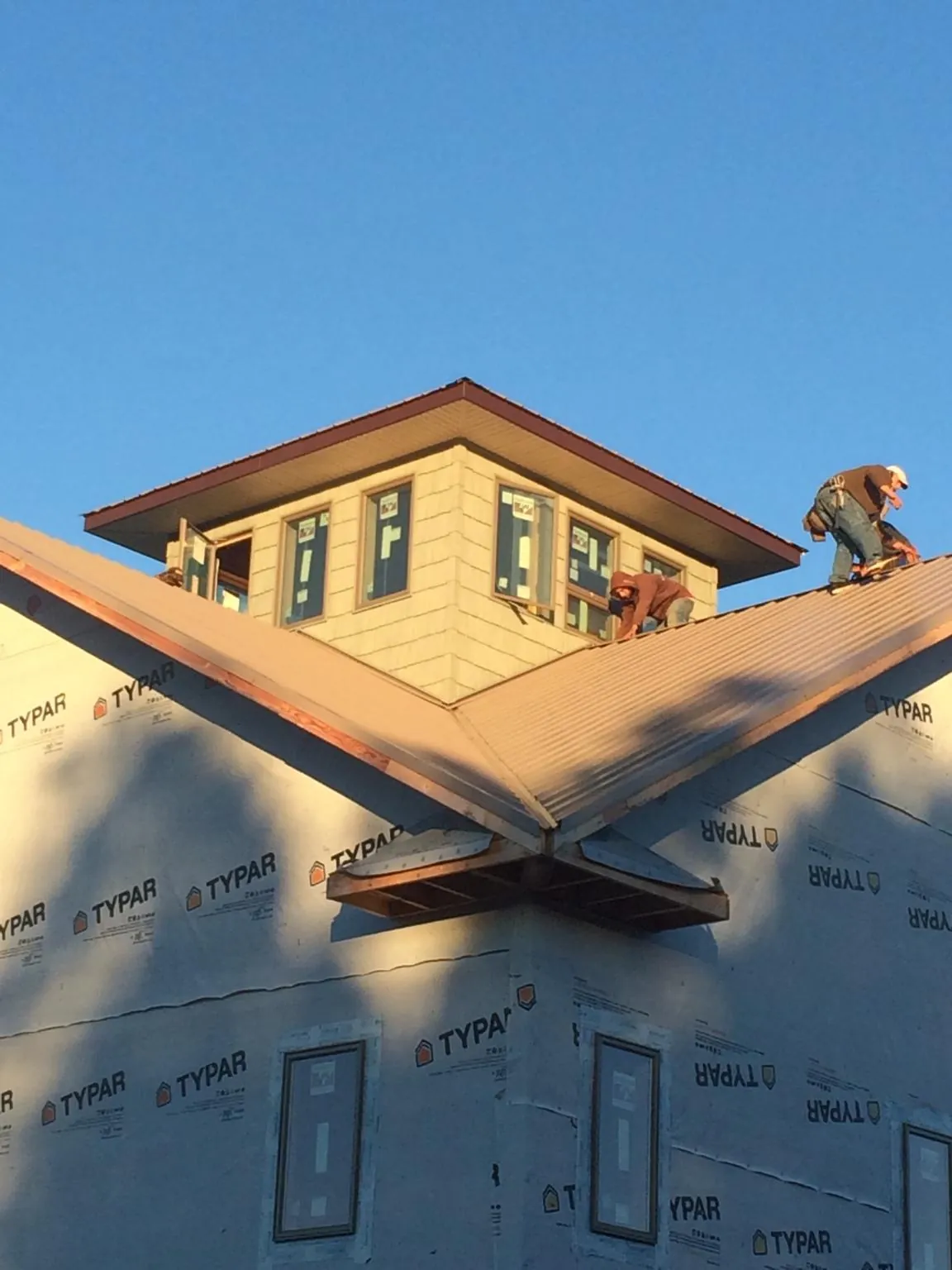 Roofers working around a rooftop cupola on a new metal roof at sunset — Roof Waterproofing in Holmdel by Roofing Brothers